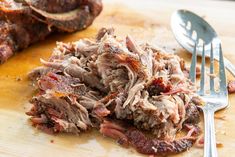 a pile of meat sitting on top of a cutting board next to a fork