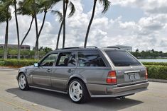 a silver car parked on the side of a road next to palm trees and water