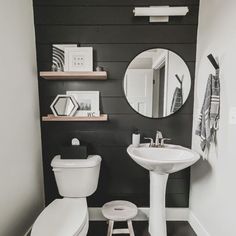 a white toilet sitting next to a sink in a bathroom under a round mirror on a wall