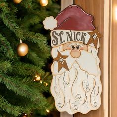 a wooden santa claus ornament hanging from a christmas tree