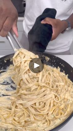 someone is cooking pasta in a skillet on the stove with a pair of tongs