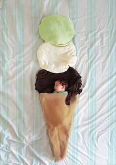 a baby is sleeping in an ice cream cone with three pillows on top of it