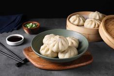 some dumplings are in a bowl on a wooden tray with chopsticks next to it