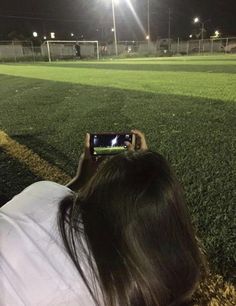 a person taking a photo with their cell phone at night on a soccer field in the dark