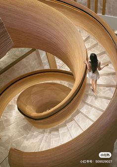 a woman is walking down a spiral staircase