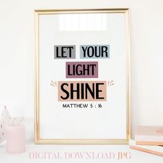 a framed poster with the words let your light shine on it next to some candles