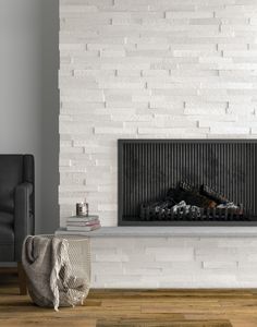 a white brick wall with a fireplace in the middle and books on the floor next to it