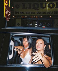 two women are sitting in the back of a car and one is pointing at something