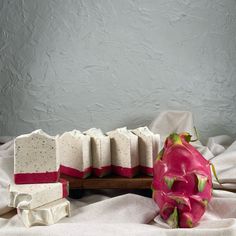 a pink dragon fruit sitting on top of a table next to soap blocks and a white towel