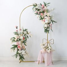 two floral arrangements on display in front of a white wall and pink chair covers with bows