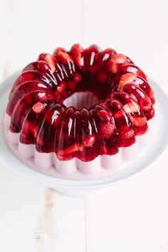 a bundt cake covered in jelly and strawberries on top of a white plate