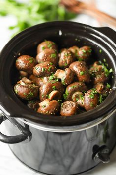 a crock pot filled with mushrooms and parsley