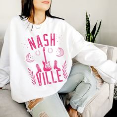 Get ready to be OBSESSED with your new 'Nashville' guitar crewneck sweatshirt. It's the cutest and most trendy way to emit all those important Nash, Tennessee vibes! This is the perfect pullover for bachelorette parties, festivals, or country concerts and makes a great gift for Country music lovers! To view similar items CLICK HERE: https://www.etsy.com/uk/listing/1184964376/nashville-skyline-tshirt-nashville? Have a look around my shop to see what else you'll love! https://www.etsy.com/uk/shop/ Band Logo Cotton Tops For Fall, Cotton Band Logo Tops For Fall, Cotton Sweatshirt For Fall Concerts, Fall Music-themed Cotton Tops, Band Logo Crew Neck Sweatshirt For Concert, Casual Cotton Sweatshirt For Concerts, Casual Band Logo Sweatshirt For Fans, Band Logo Cotton Sweatshirt For Fans, Music-themed Cotton Crew Neck Sweatshirt