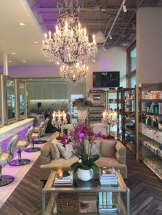 a chandelier hanging from the ceiling in a store filled with furniture and flowers