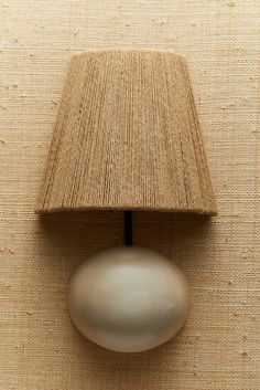 a lamp that is on the side of a wall next to a beige cloth shade