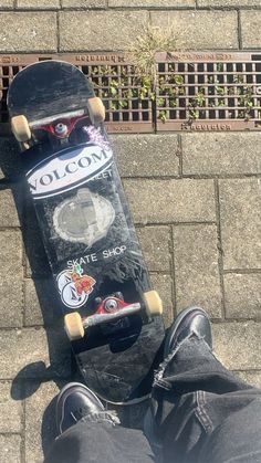 a skateboard with some stickers on it sitting next to someone's feet