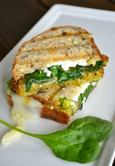 a sandwich with spinach and cheese on a white plate