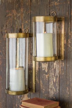 an old wooden wall with two candle holders on it and books sitting next to it