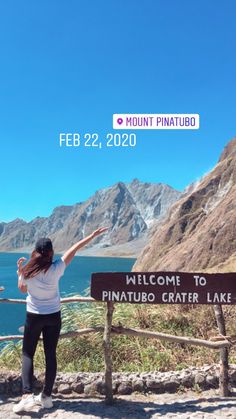 a woman standing at the top of a mountain with her arms up in the air