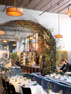 a restaurant with tables and chairs covered in white tablecloths, plants on the wall