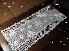 a white doily with snowflakes on it sitting on top of a wooden table