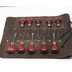 an assortment of red knobs and wrenches on a brown cloth with black handles