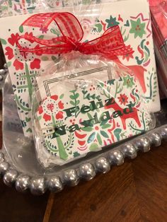 a gift bag with a red bow on it sitting in front of some christmas decorations