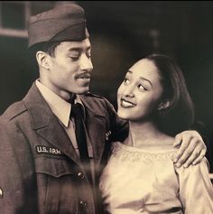 an old black and white photo of a man in uniform standing next to a woman