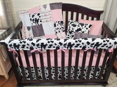 a baby crib with pink, black and white bedding