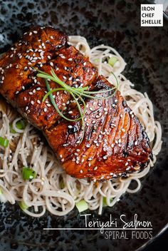 a black plate topped with meat and noodles