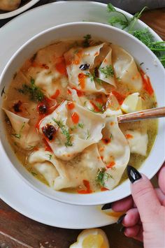 a white bowl filled with dumplings on top of a wooden table