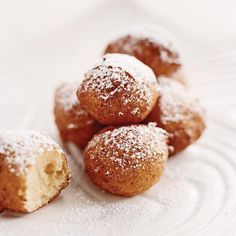 powdered sugar covered doughnuts on a white plate