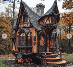 a small wooden house sitting on top of a pile of leaves next to a forest