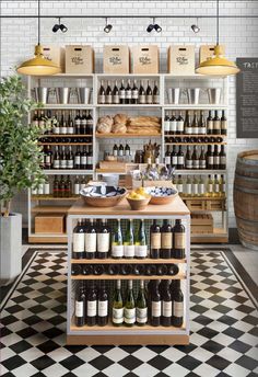 a store filled with lots of bottles of wine and bread on shelves next to a black and white checkered floor