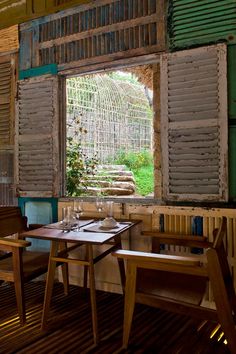 a table and chairs in front of a window with shutters on the outside wall