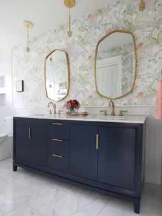 a bathroom with two sinks and mirrors on the wall above it is decorated in floral wallpaper