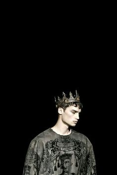 a man with a crown on his head standing in front of a black background,