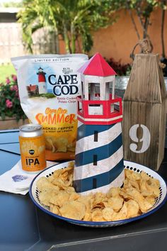 a plate with chips and a lighthouse made out of paper on the table next to it