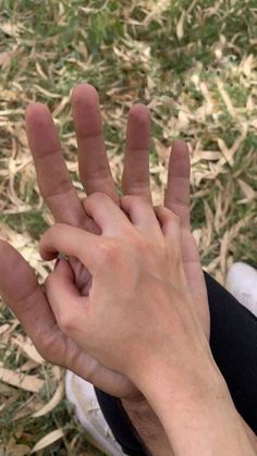 a person is holding their hand up in the air while sitting on the ground outside