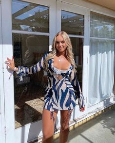 a woman in a blue and white dress is posing for the camera with her hands out