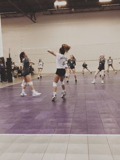 some girls are playing volleyball in an indoor court while others watch from the sidelines