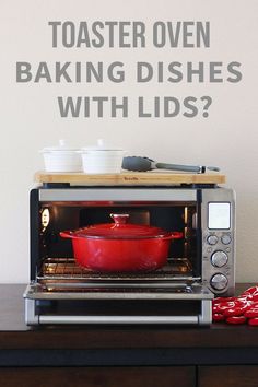 a toaster oven sitting on top of a wooden table next to a red pan