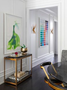 a dining room table and chairs with art on the wall