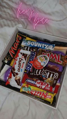 a box filled with assorted candy on top of a bed