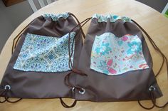 two drawstring bags sitting on top of a wooden table