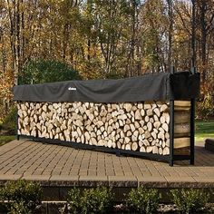 a large pile of logs sitting on top of a wooden deck in front of trees