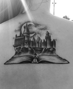 the back of a woman's neck with an open book and hogwarts on it