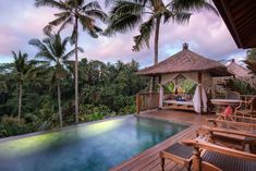 an outdoor pool surrounded by palm trees and lounge chairs with a gazebo in the background