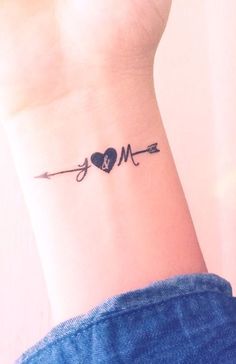 a heart and arrow tattoo on the wrist