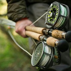 a man holding two fishing rods and reels